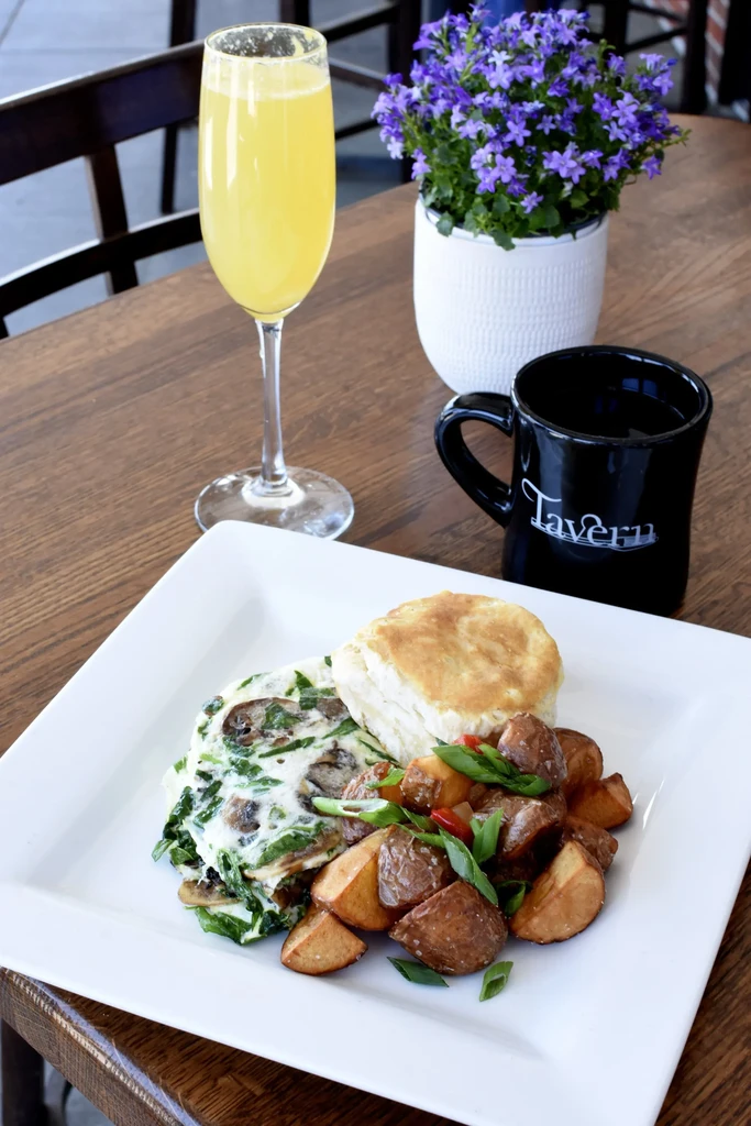 Brunch plate with omelet, biscuit, roasted potatoes, mimosa, and coffee mug.