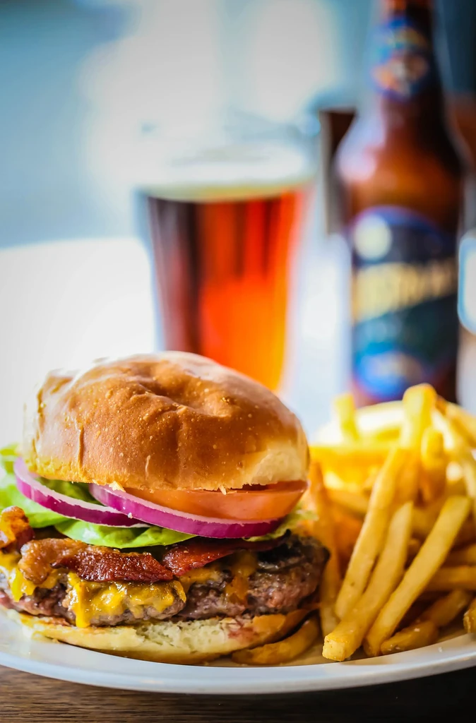 Close-up: Gourmet burger, french fries, and blurred beer.