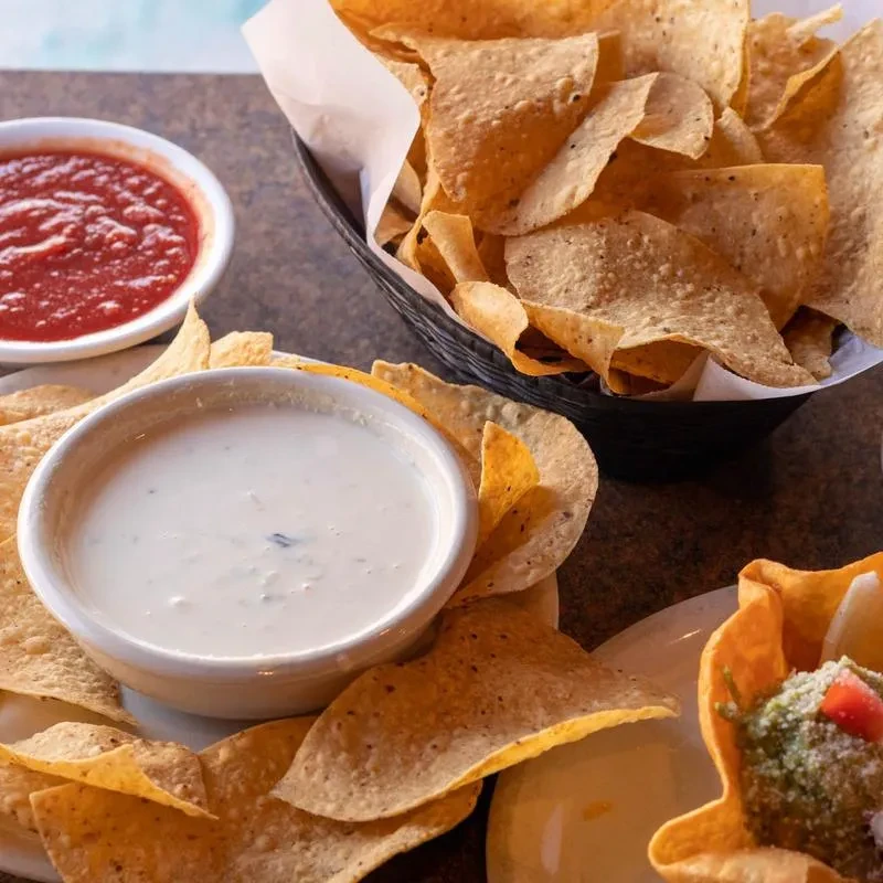 Overhead view of classic Mexican appetizers: chips, queso, salsa, guacamole.