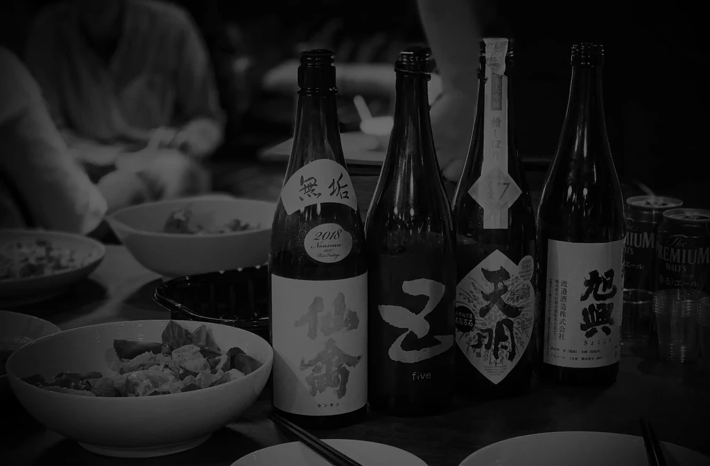 Four labeled bottles, food bowls, and chopsticks on a black and white table.