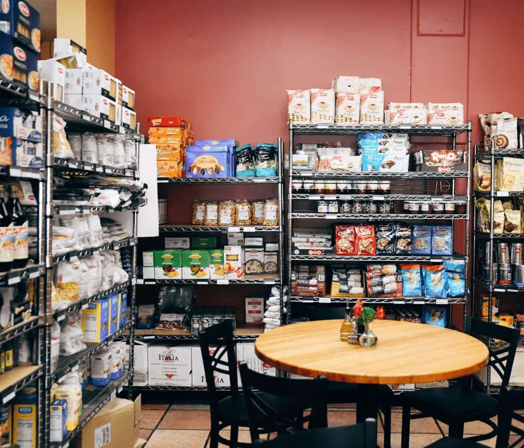 Italian market interior with stocked food shelves and a small round table.