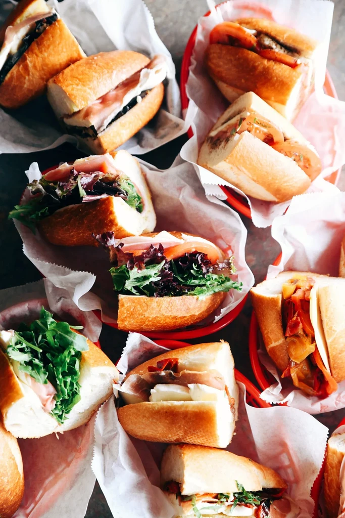 Overhead view of various halved sub sandwiches in red plastic baskets.