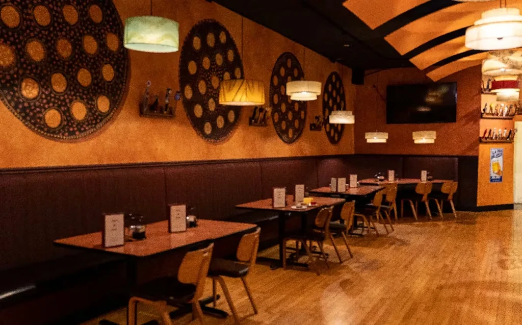 Warm restaurant interior with orange wall, circular decor, and striped ceiling.