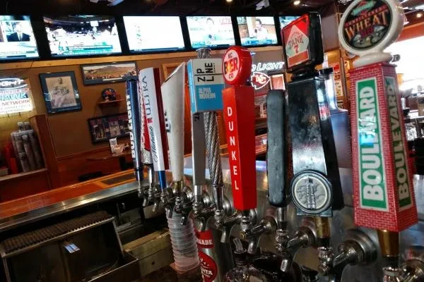 Multiple beer taps with brand names visible in a sports bar.