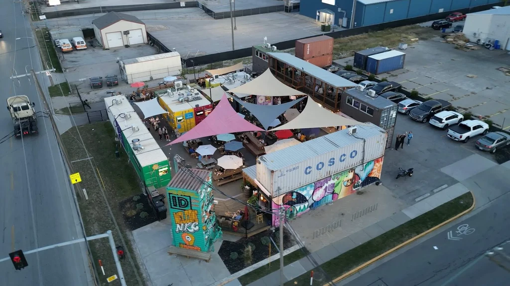 Vibrant aerial view: busy outdoor food market built with shipping containers.