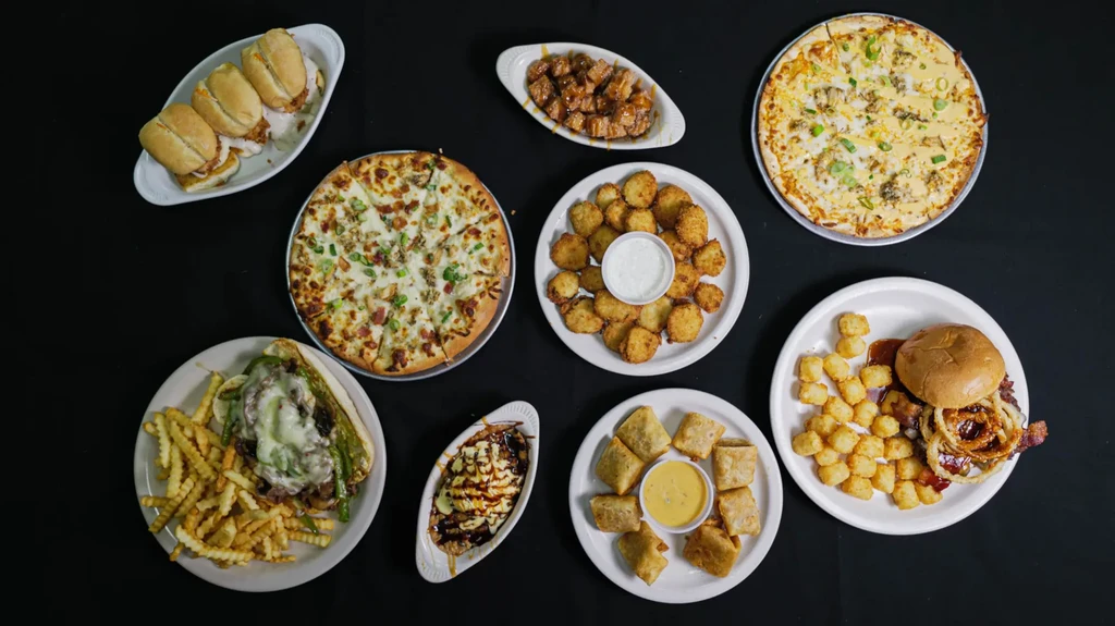 Overhead view of ten diverse dishes on white plates against black.