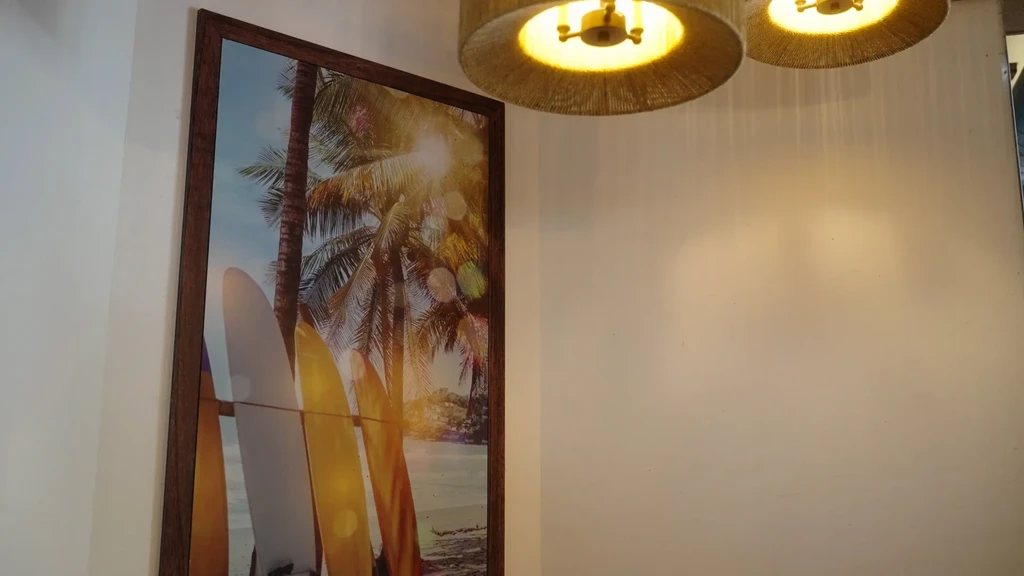 Framed tropical beach art with surfboards, palm trees, and warm ceiling lights.