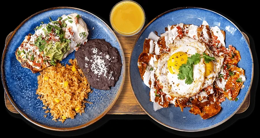 Top-down view of two colorful Mexican meals and a glass of juice.
