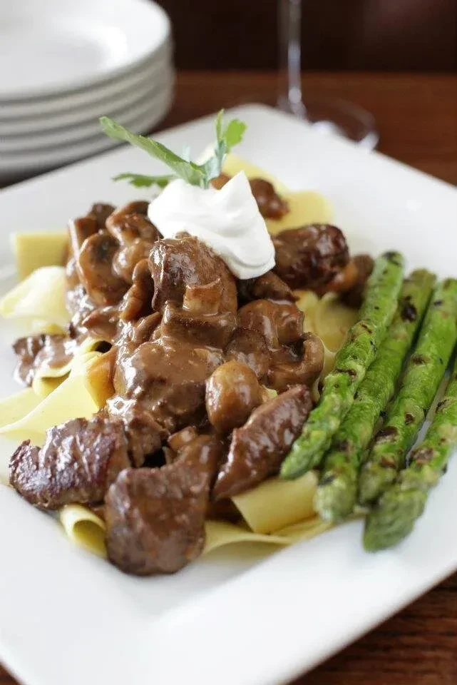 Beef and mushroom stew over noodles, with cream and asparagus.