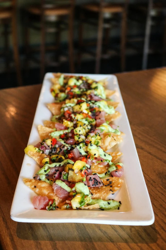 Crispy wonton chips with tuna poke, mango, green sauce, and sesame seeds.