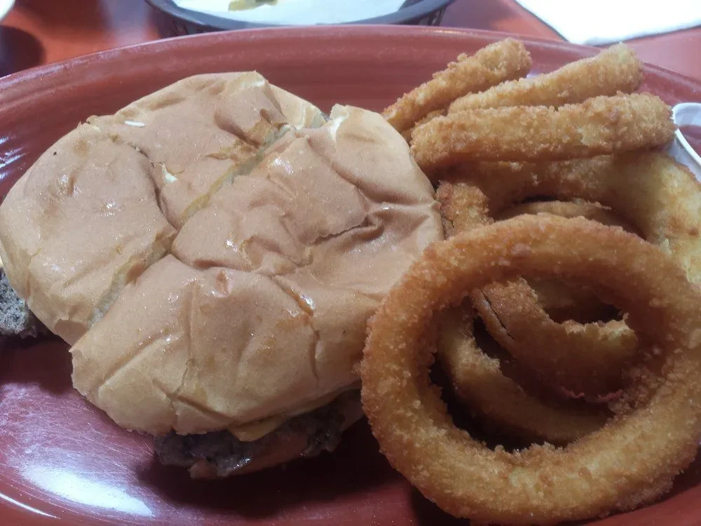 Burger with melted cheese and a side of crispy onion rings.