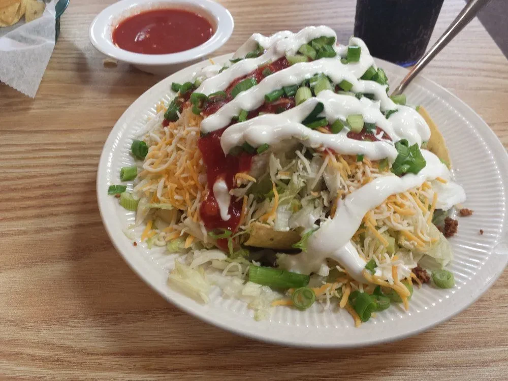 Overhead view of a loaded taco salad with meat, cheese, salsa, sour cream.