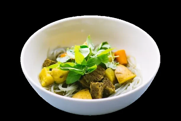 Vietnamese beef stew with beef, carrots, potatoes, noodles, and basil.