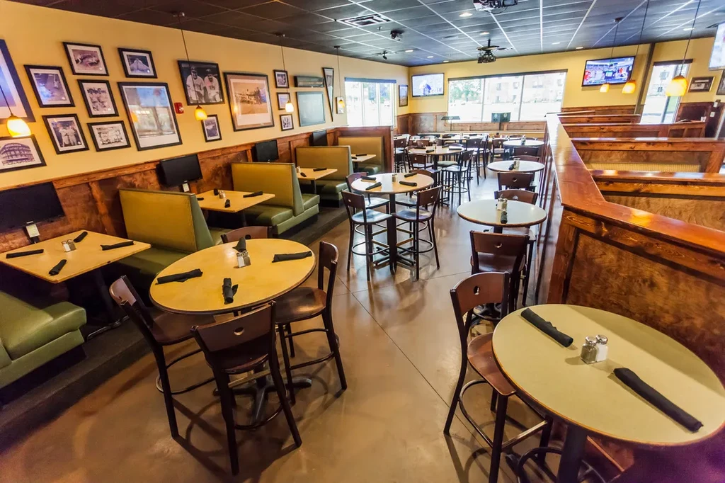 Empty casual sports bar with booths, high-top tables, and wall TVs.