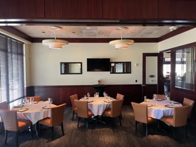 Modern private dining room with set tables, two-toned walls, and pendant lights.