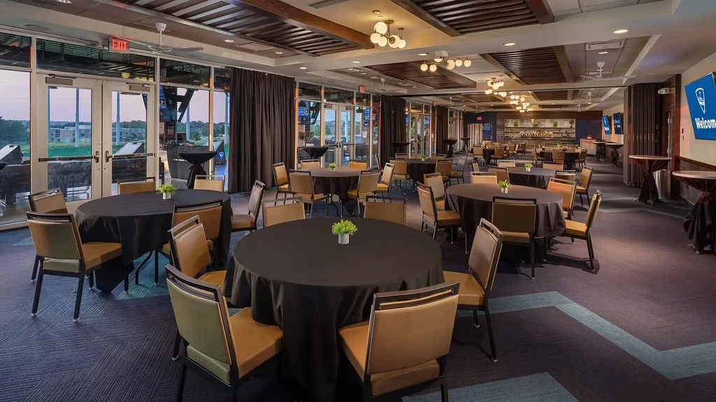 Modern restaurant bar with tables overlooking golf bays and welcome screen.
