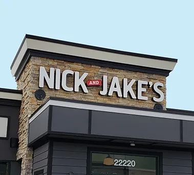Close-up of NICK and JAKE'S sign on a stacked stone building.