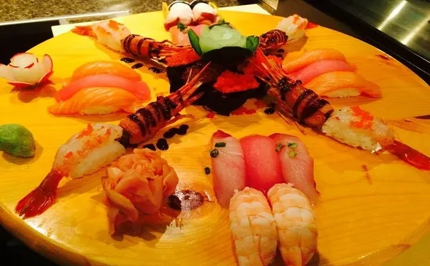 Elaborate wooden platter filled with nigiri sushi, sashimi, and garnishes.