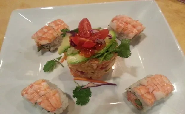 Colorful grain salad with avocado, tomatoes, and shrimp sushi rolls.