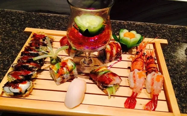 Elaborate sushi and sashimi platter on wood with deep-fried rolls and shrimp.