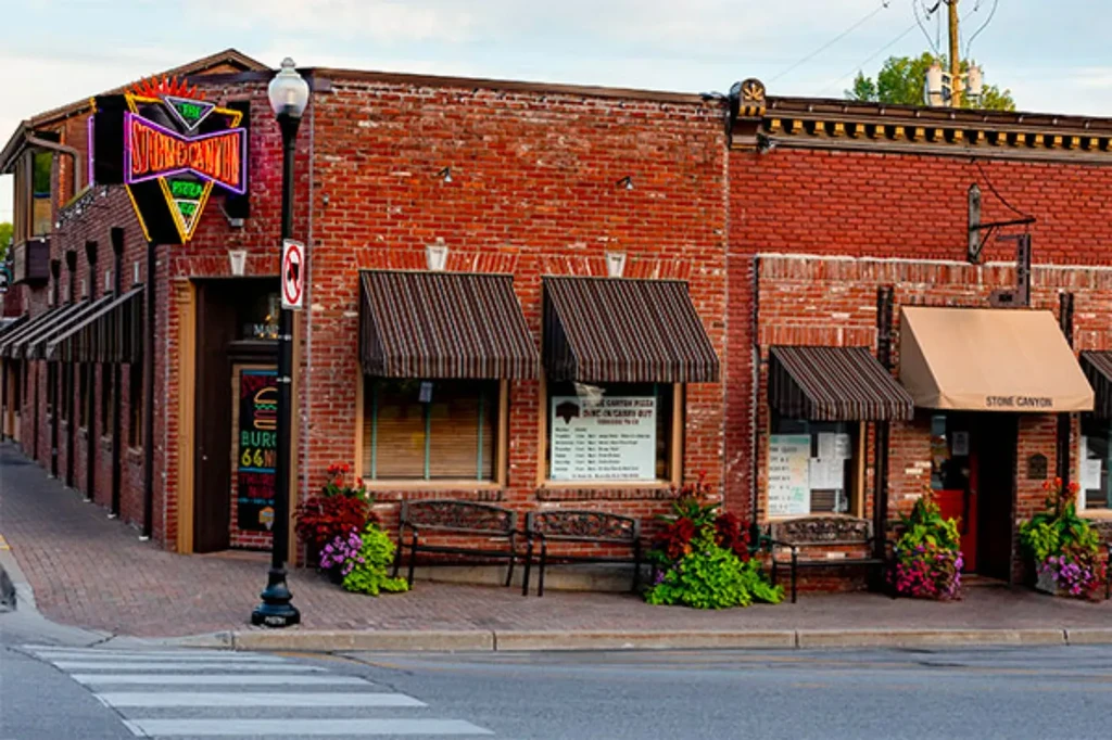 Adjacent red-brick Stone Canyon Pizza buildings with neon signs and awnings.