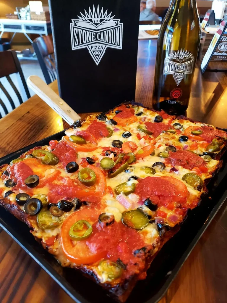 Rectangular deep-dish pizza, pepperoni, olives, jalapeños, Stone Canyon logo.