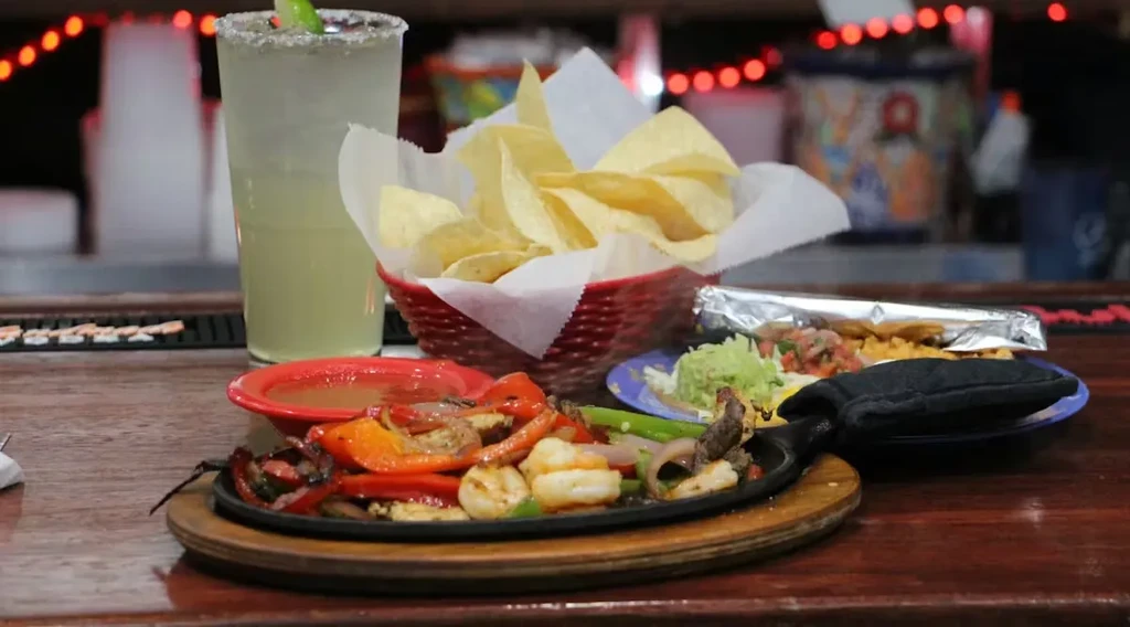 Sizzling shrimp and meat fajitas with chips, guacamole, and a margarita.