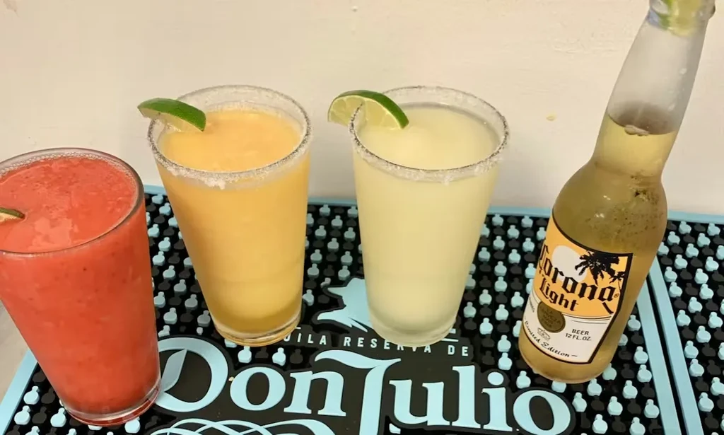 Four alcoholic drinks: frozen, margarita, beer, on a tequila bar mat.
