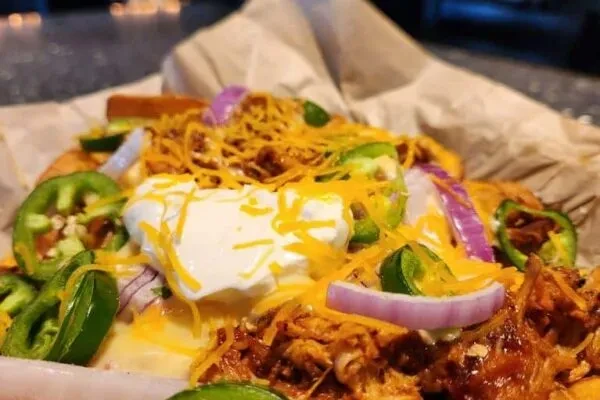 Loaded nachos with pulled meat, cheese, jalapeños, and sour cream.
