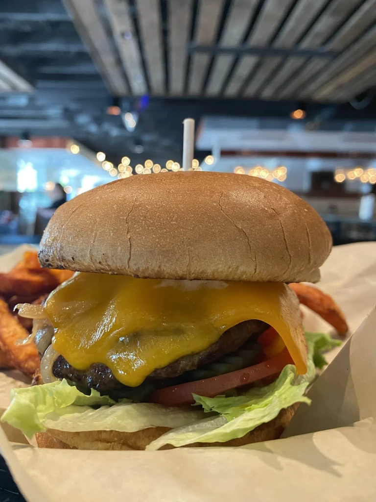 Cheeseburger with melted cheese, lettuce, tomato, and sweet potato fries.