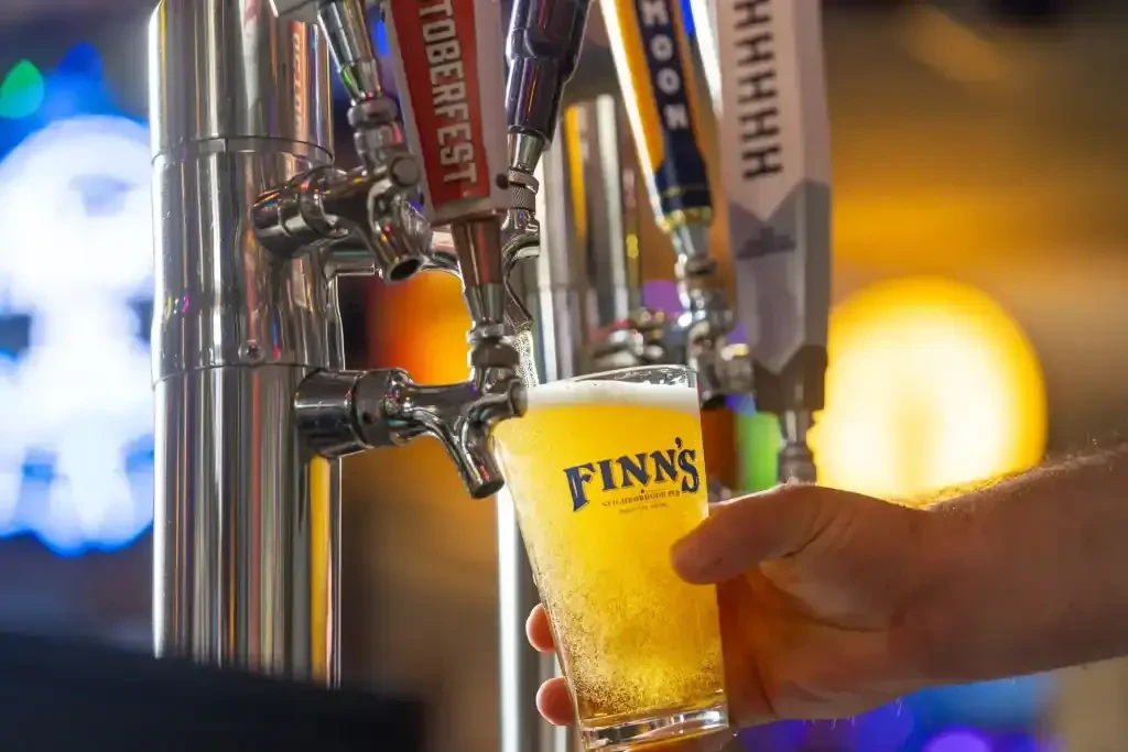 Hand holds glass catching frothy beer from Oktoberfest tap.