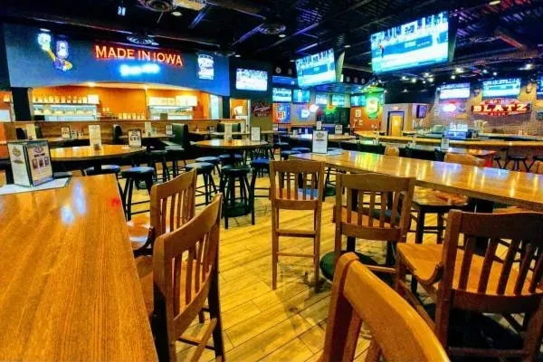 Spacious, empty sports bar with numerous TVs and 'MADE IN IOWA' neon.