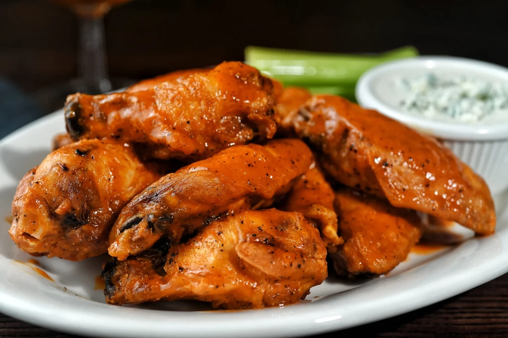 Close-up plate of buffalo chicken wings with celery and blue cheese dip.