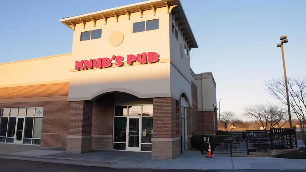 Modern Knub's Pub building with red sign, patio, and sunny blue sky.