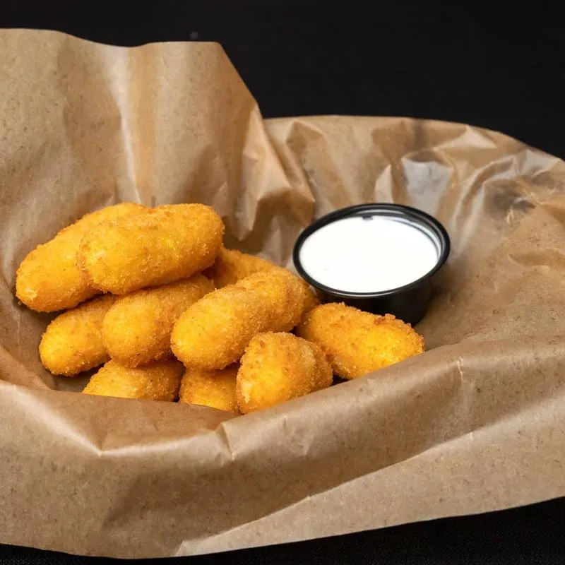 Deep-fried breaded appetizers with dipping sauce in a rustic basket.