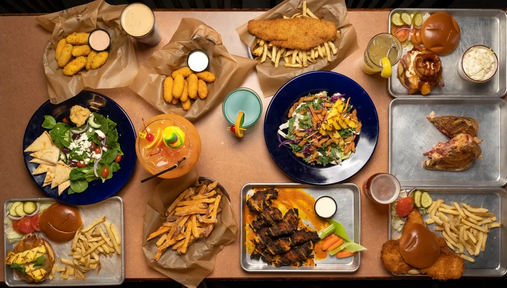 Overhead view: a restaurant table covered with diverse food and drinks.