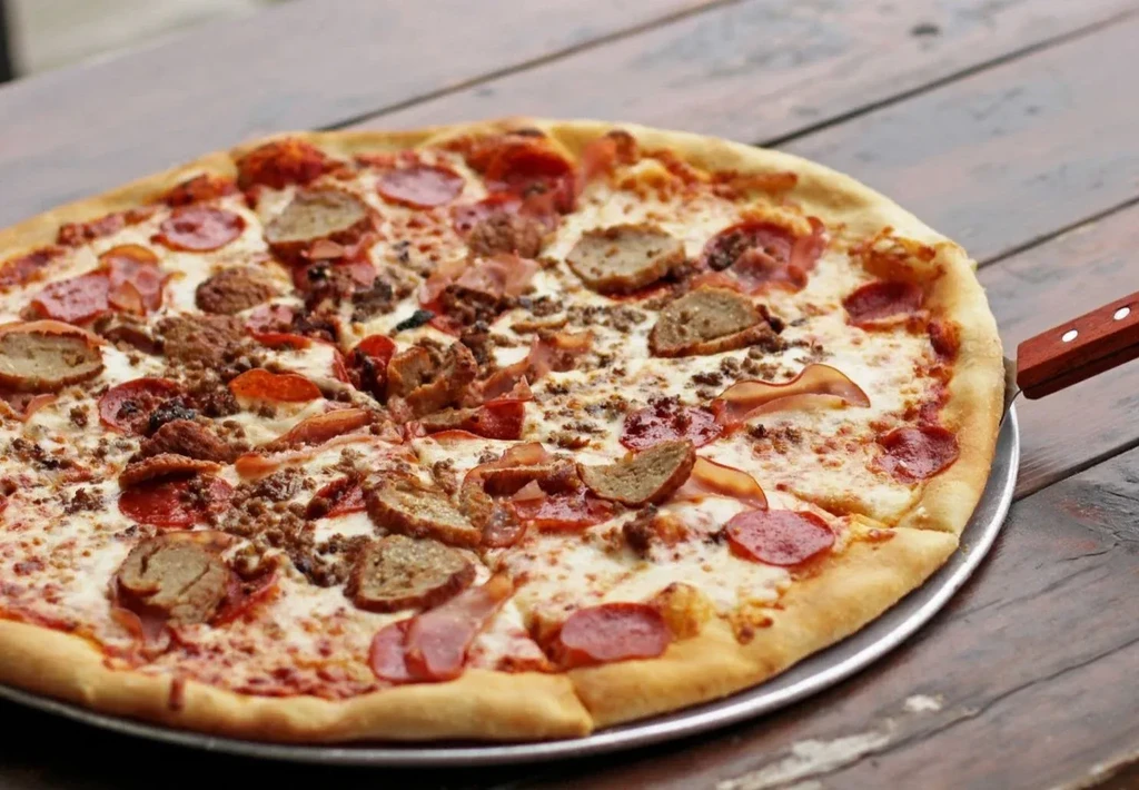High-angle close-up of a large, freshly baked pizza with various meat toppings.