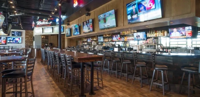 Spacious modern sports bar interior with long bar, TVs, and seating.
