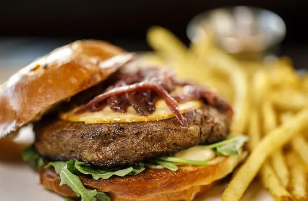 Gourmet burger with caramelized onions, arugula, and golden french fries.