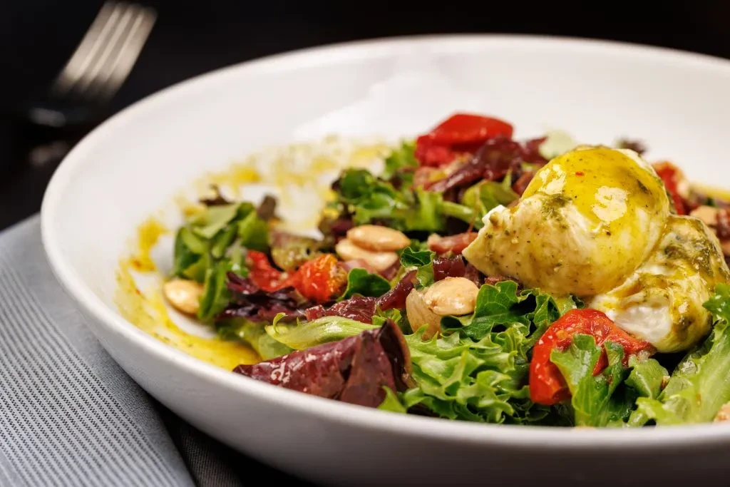 Fresh, vibrant salad with greens, burrata, almonds, and herb dressing.