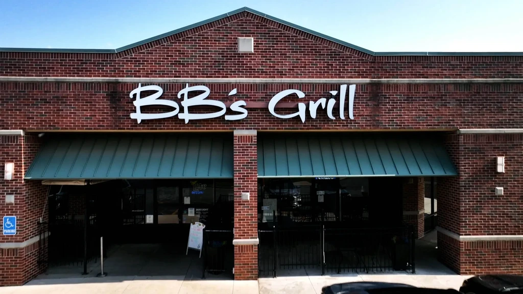 Red brick BB's Grill restaurant with white sign and green awnings.
