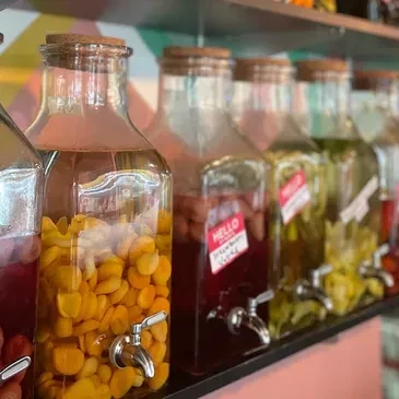 Row of clear glass dispensers with colorful fruit drinks.