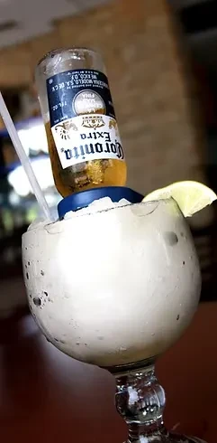 Close-up of a frozen Corona-rita cocktail with lime garnish.