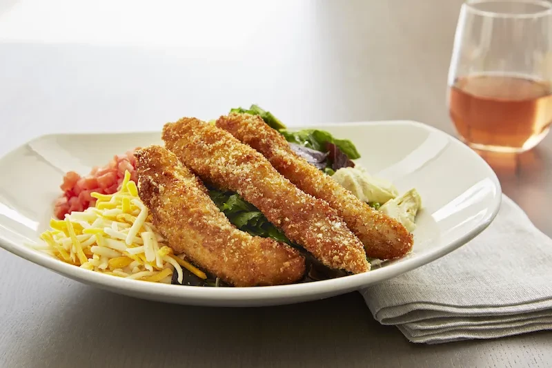 Breaded strips, mixed salad, shredded cheese, and diced tomatoes.