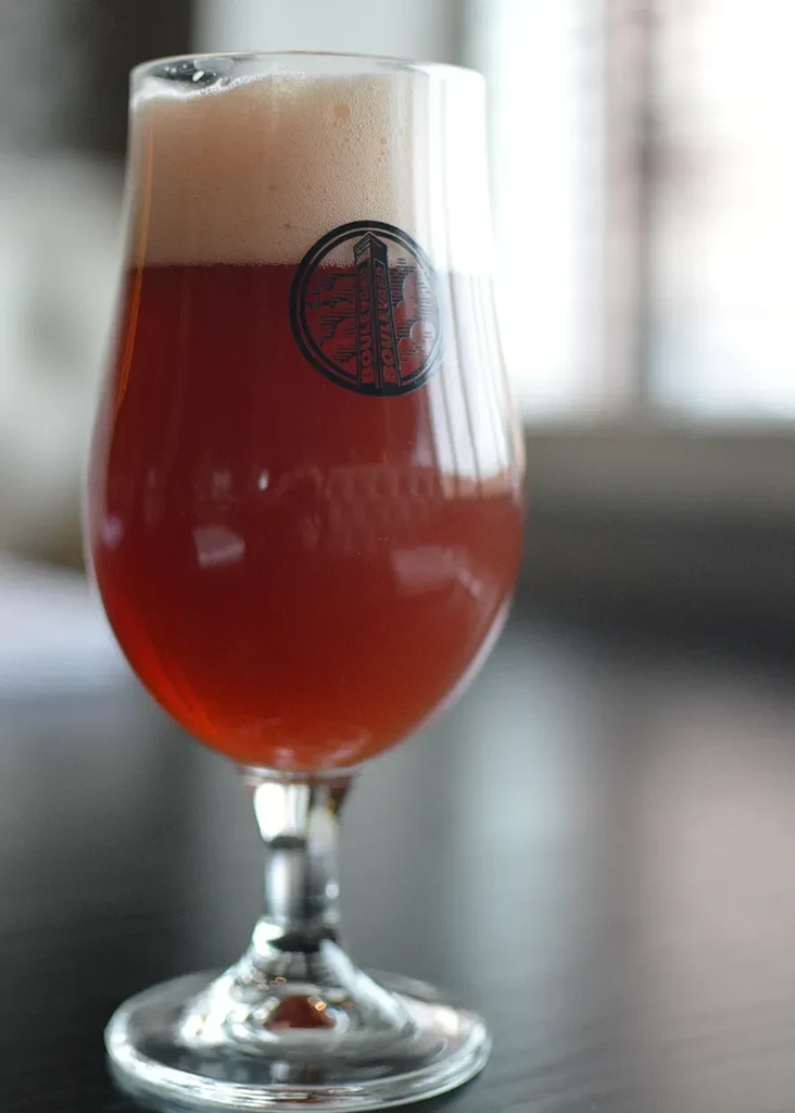 Amber beer in a Boulevard tulip pint glass with thick white foam.
