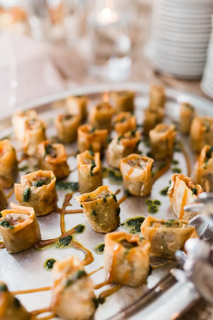 Bite-sized appetizers on a silver tray, garnished with green and amber sauces.