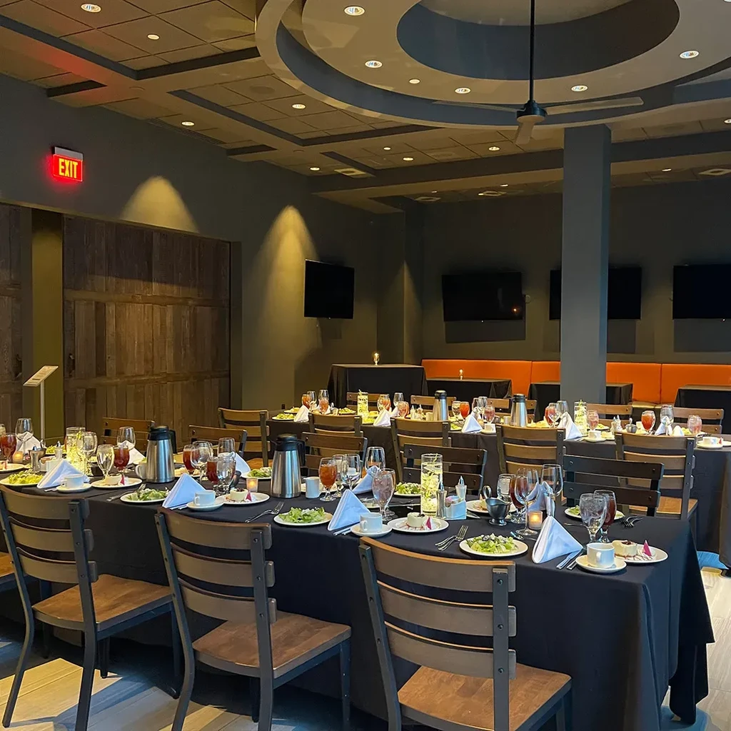 Empty banquet hall with set tables, chairs, and orange booth seating.