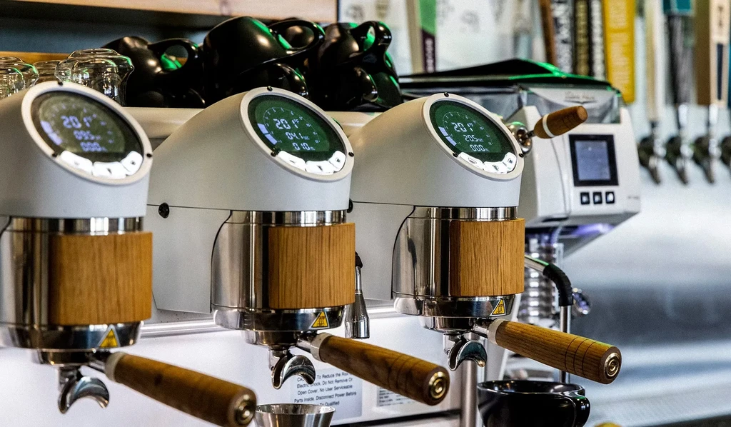 Three sleek espresso machines with wood accents and digital screens.