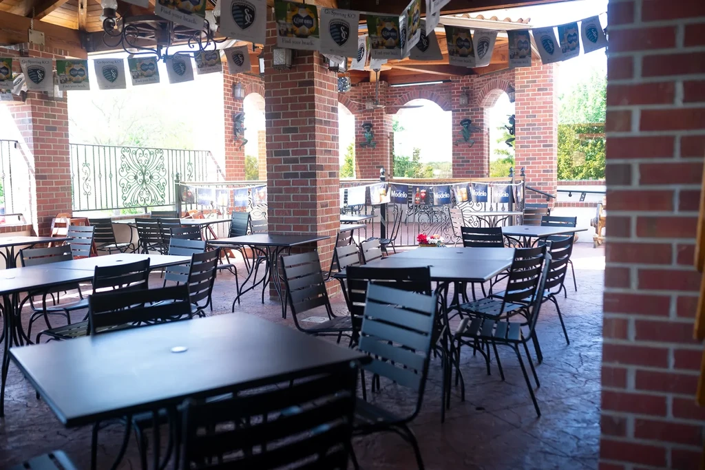 Empty outdoor patio with dark tables, chairs, and brand banners.