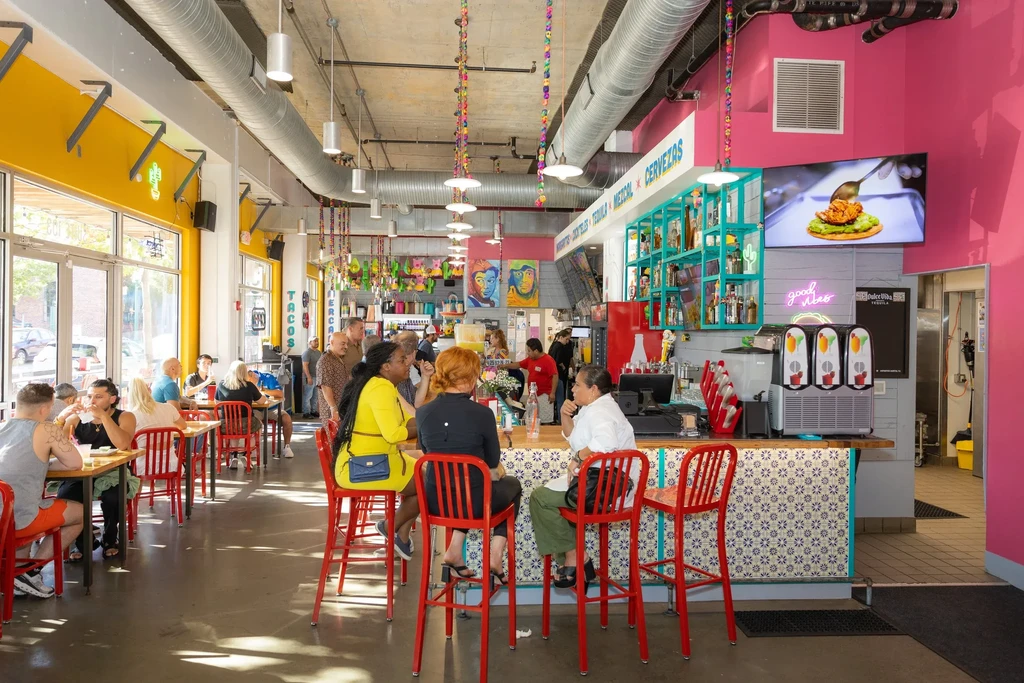 Vibrant, busy restaurant interior featuring a bar, tables, and patrons.